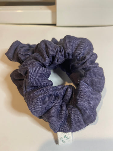 Small dark blue linen scrunchie hair accessories on a white background. has small white tag sewn in the is white with green writing simple sunday