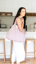 Load image into Gallery viewer, Shell coloured, 100% linen beach bag, Australian Made, on ladies shoulder.  Lady standing in front of a white kitchen bench with timber accents
